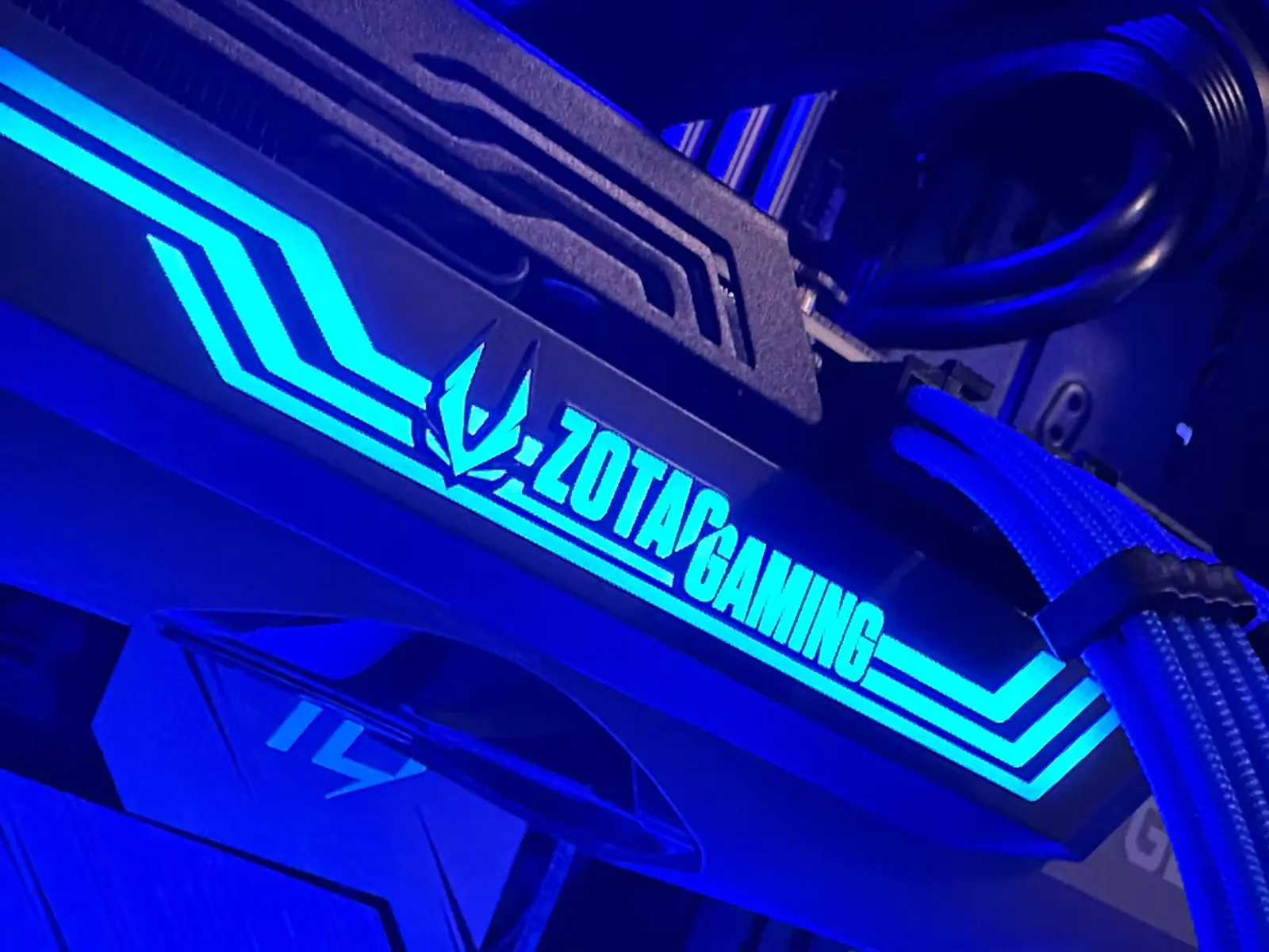 Close-up of a Zotac Gaming graphics card glowing blue inside a FEG build