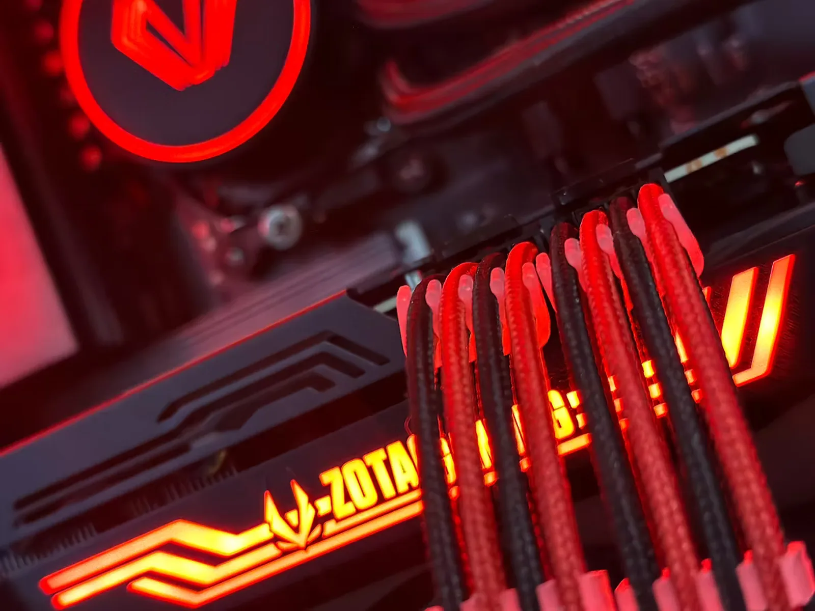 Red-lit PC interior with a Zotac Gaming graphics card and red sleeved cables